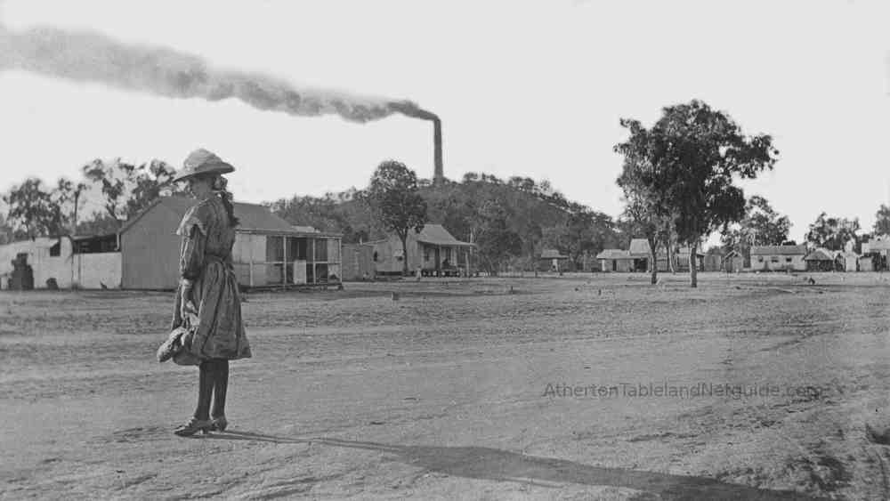 Girl or young woman in the foreground in the town of Chillagoe with smelters in the background